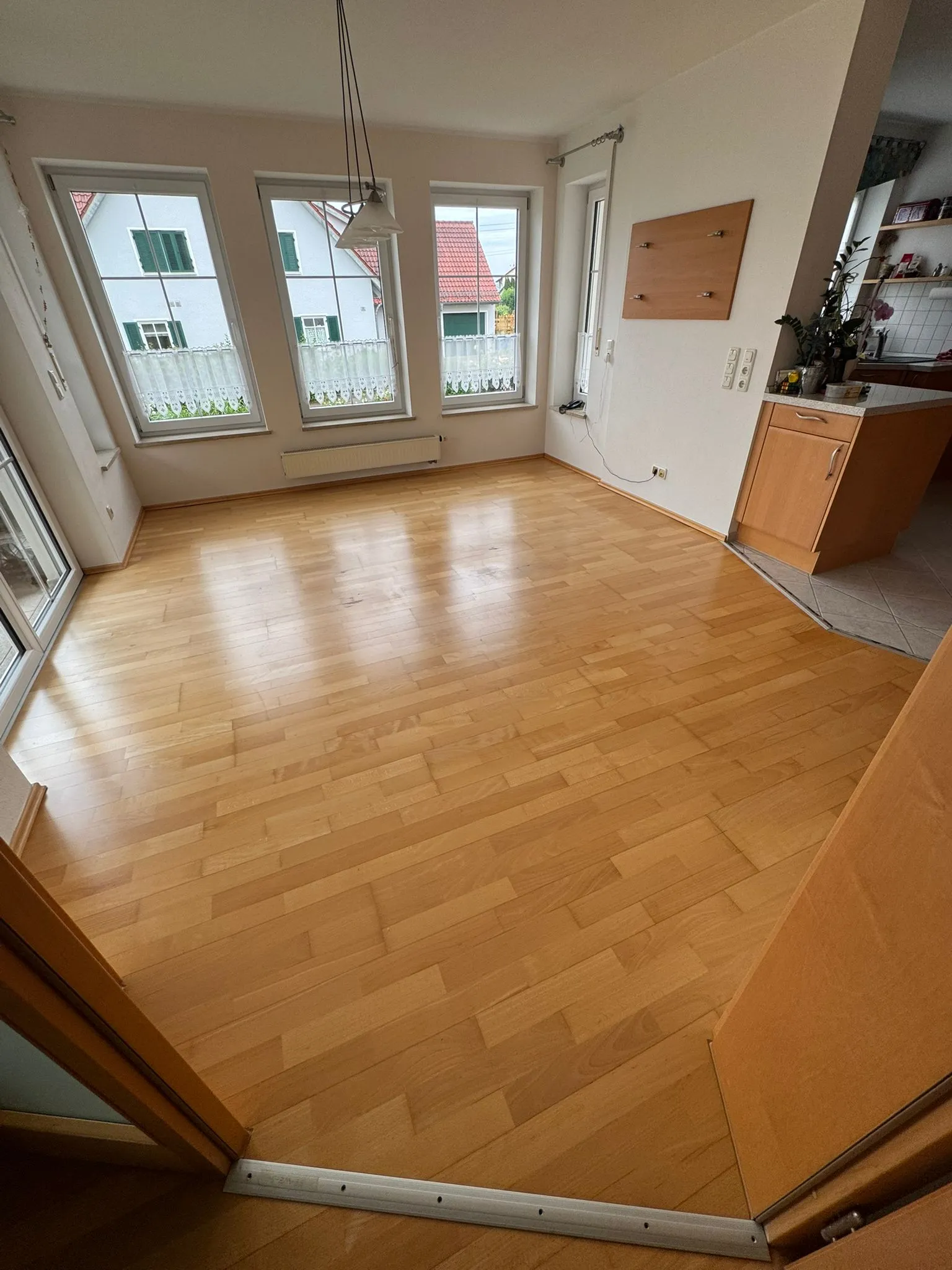 Esszimmer mit honigfarbenem Parkettboden und drei Fenstern
