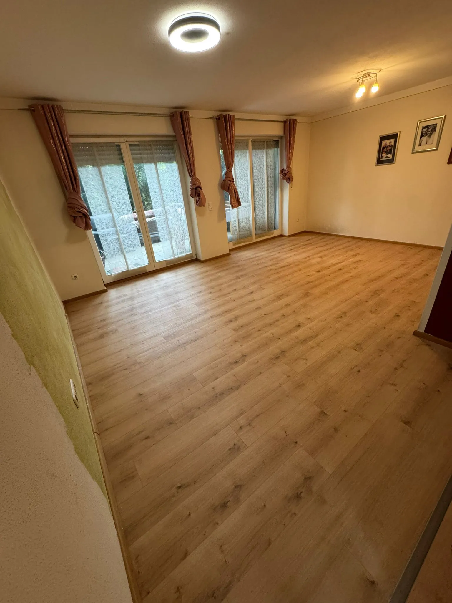 Wohnzimmer nach dem Verlegen heller Eichendielen mit Bildern und Vorhängen