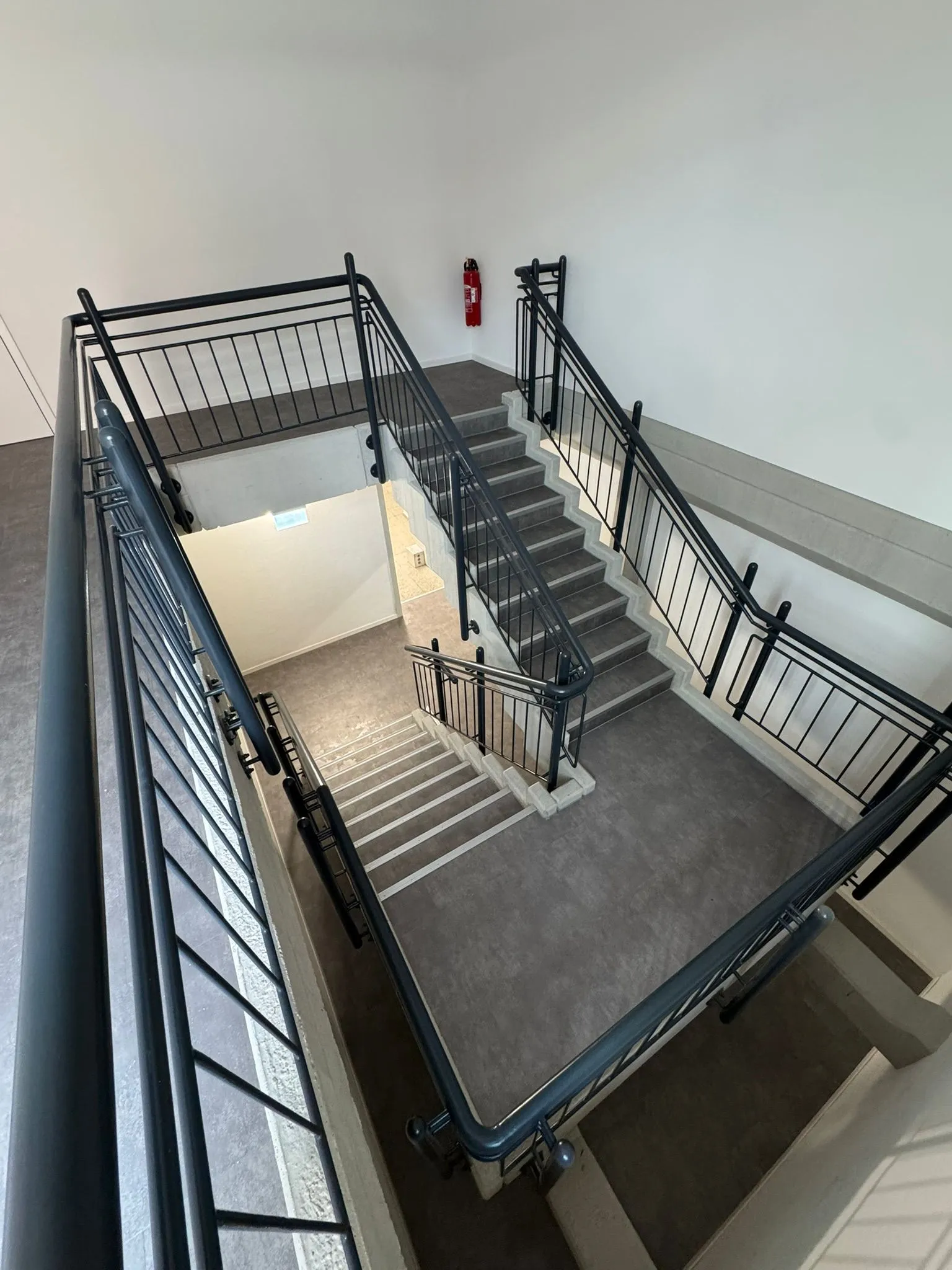 Neubau-Treppenhaus mit grau-marmoriertem Belag auf Stufen und Podesten