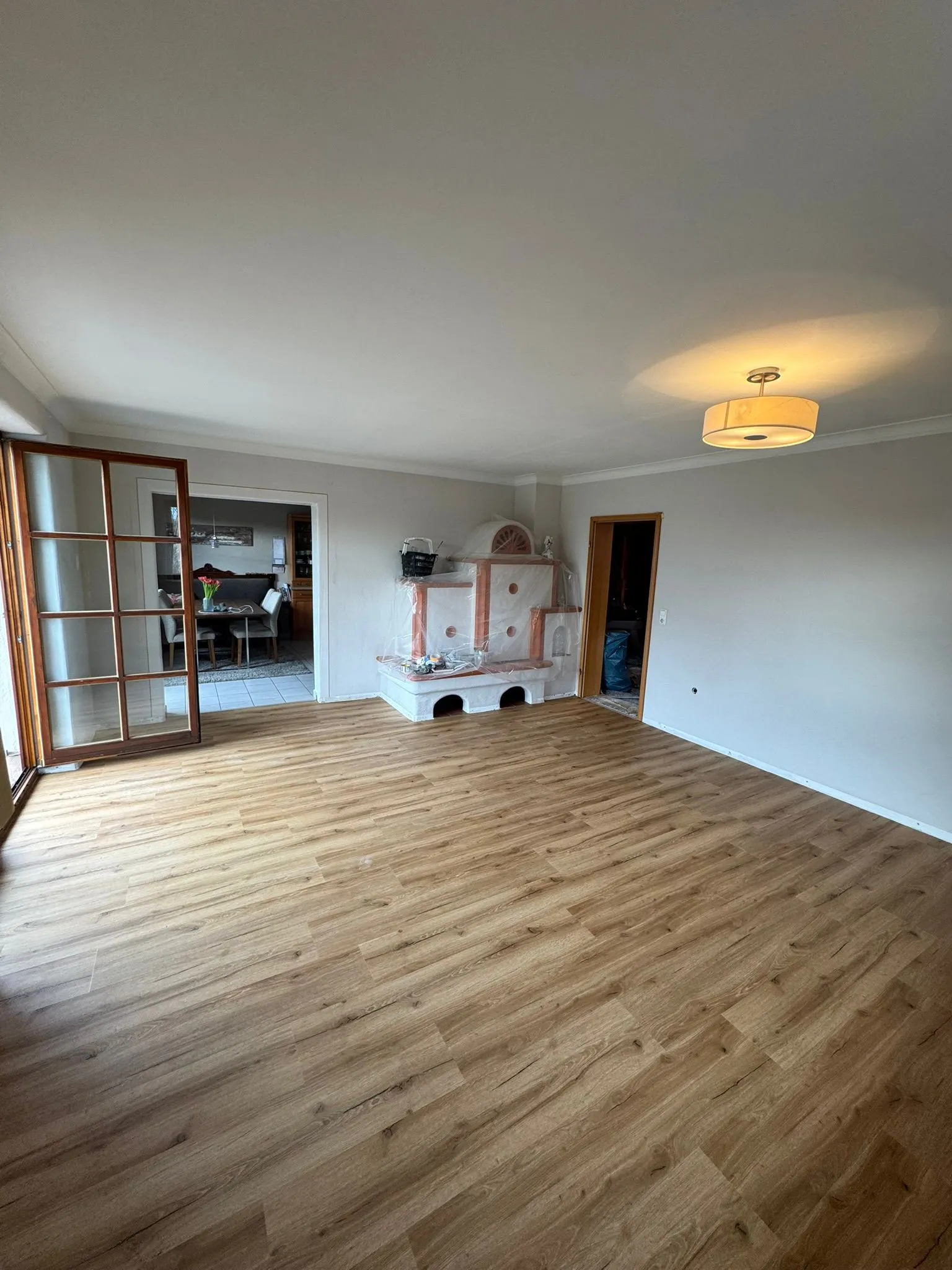 Wohnzimmer mit goldenen Eichendielen rund um einen restaurierten Kachelofen